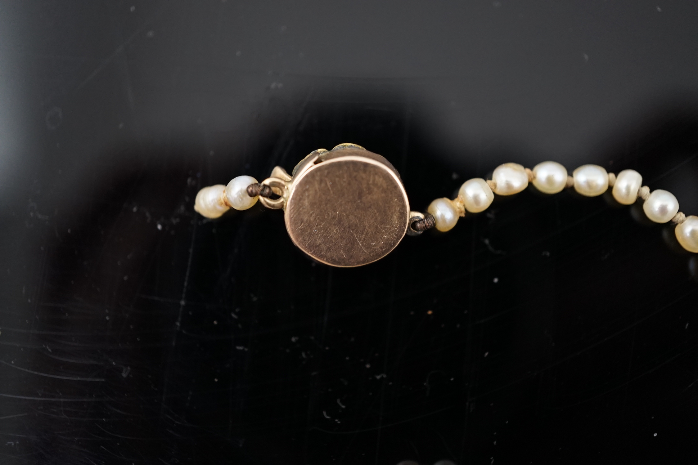 A Victorian single strand graduated natural saltwater pearl necklace, with seed pearl and enamel set gold clasp